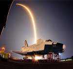 The SpaceX launch of its Falcon 9 rocket and an unmanned Dragan capsule in May lights up the sky as it streaks over a model of NASA's now-retired space shuttle (Credits: Craig Rubadoux).