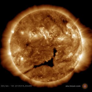 A coronal hole, seen as the large dark region in the center of this image, is spewing solar wind in the direction of Earth (Credits: NASA SDO/AIA).