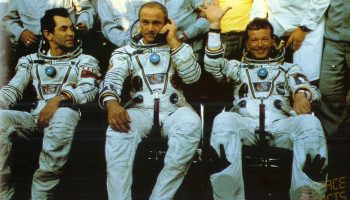 Jean-Loup Chretien (right) waves to well-wishers in the aftermath of his safe landing. Commander Vladimir Dzhanibekov (center) reports by telephone the flight’s successful completion, whilst Aleksandr Ivanchenkov looks on (Credits: SpaceFacts.de/Joachim Becker).