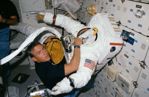 As 51I’s ambitious space salvage operation took shape, one thing was certain: the mission would be EVA-intensive and RMS-intensive. Pictured on Discovery’s middeck with one of the space suits, astronaut Bill Fisher would perform delicate electrical work on the crippled Leasat-3 (Credits: NASA).