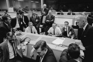 Flight controllers—with Flight Director Chris Kraft seated at center—watch their monitors in dismay after the loss of the Agena on 25 October 1965. The incident led to the development of a new plan to fly a rendezvous mission between two manned craft, Gemini VI-A and Gemini VII (Credits: NASA).