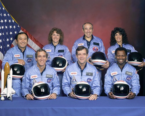 The Challenger STS 51-L crew, as it should be remembered: positive and brilliant individuals, happily striving to explore space and further humanity’s reach into the Universe. In the back row (lef to right) Ellison S. Onizuka, Sharon Christa McAuliffe, Greg Jarvis, and Judy Resnik. In the front row (lefto to right) Mike Smith, Dick Scobee, and Ron McNair (Credits: NASA).