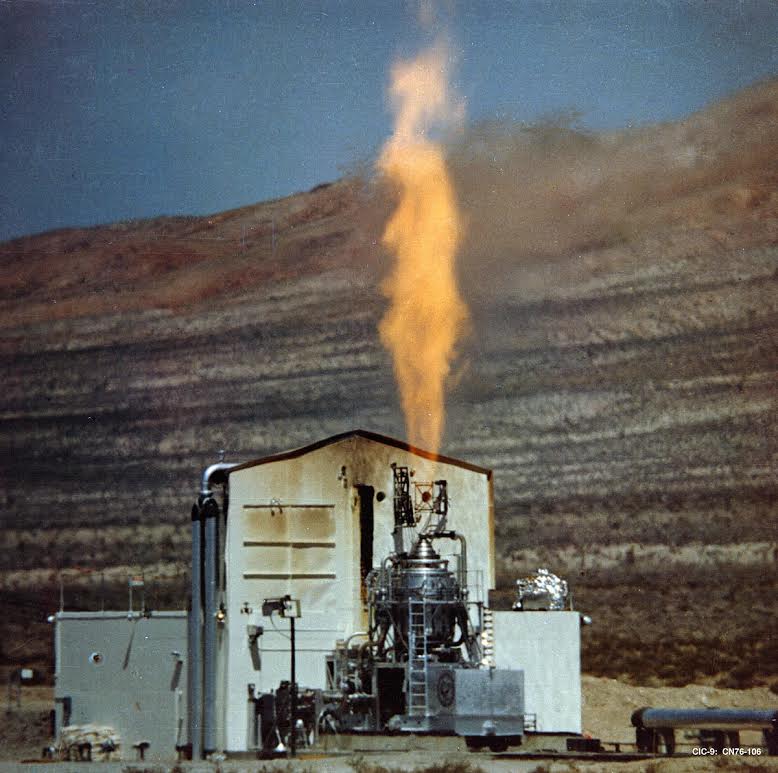 The Rover Kiwi-A full power test conducted at Jackass Flats located on the Nevada Test Site on July 1, 1959. The hydrogen exhaust plume that blurs out the mountains in the background is mostly invisible and dwarfs the visible central column. (NASA)