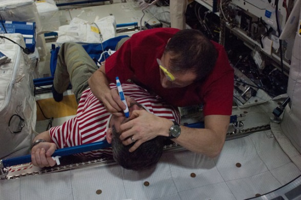 Expedition 34/35 Flight Engineer Tom Marshburn of NASA performs a tonometry eye exam on Chris Hadfield of the Canadian Space Agency in the Columbus module of the International Space Station. Tonometry measures intraocular eye pressure. Credits: NASA